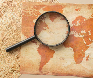 Photo of a magnifying glass on a world map in sepia by Monstera